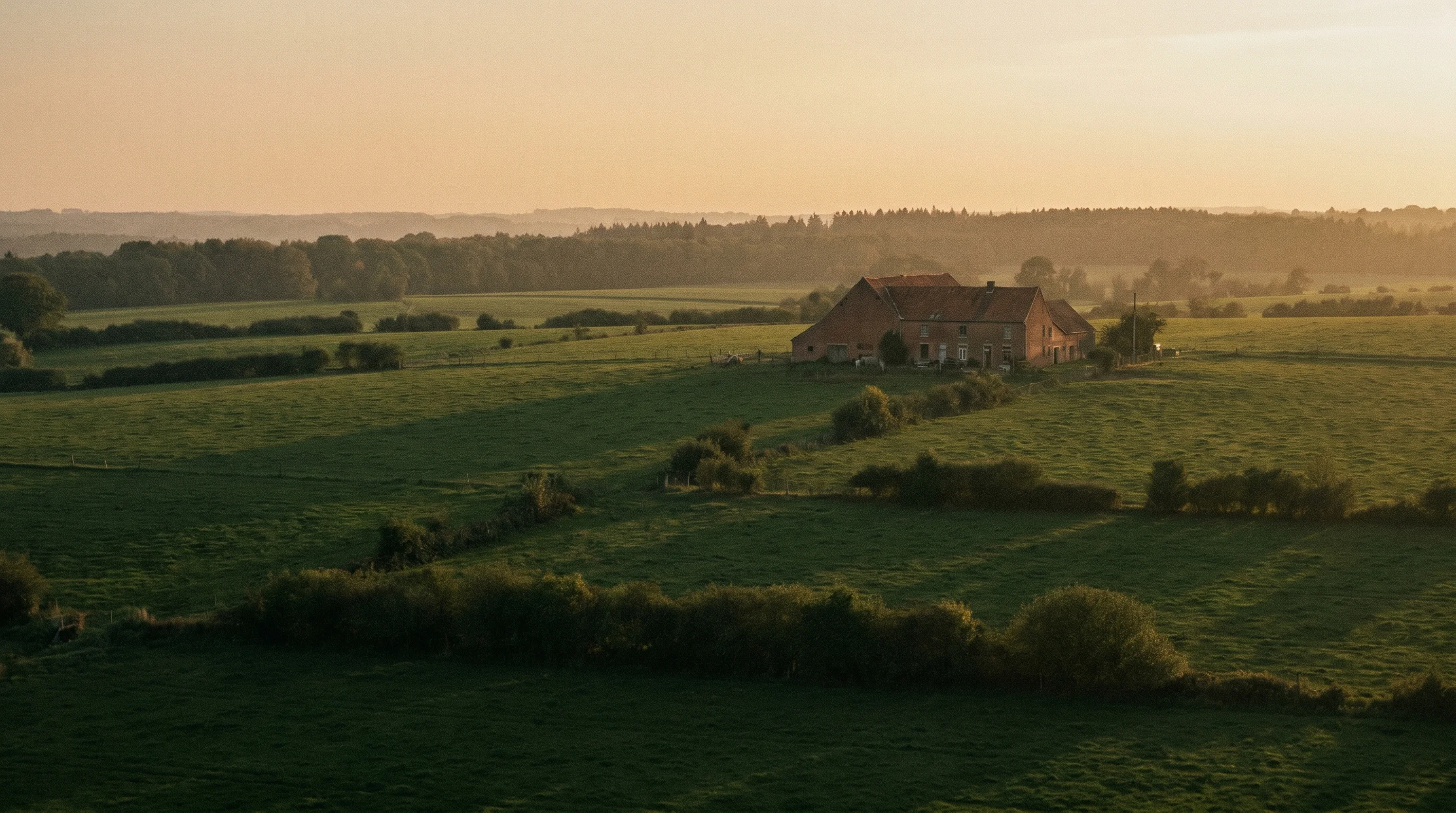 Campagne wallonne avec fermette en briques au coucher du soleil